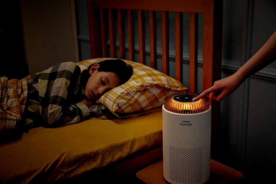 A person sleeping next to an Airmega 50 air purifier at night.