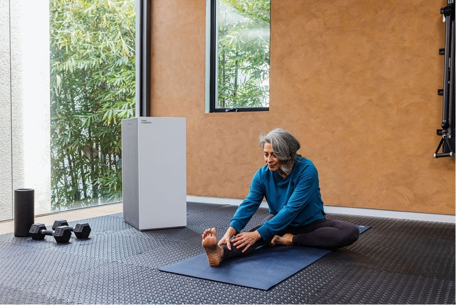 Airmega ProX with a woman stretching in a large room.