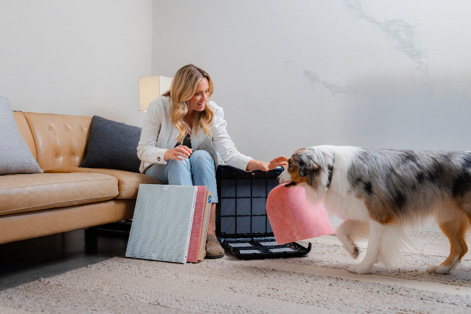 A woman opening her Airmega and taking out the filter with her dog.