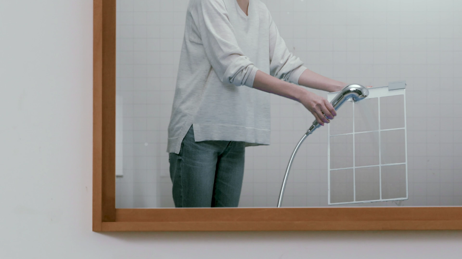 A person cleaning a prefilter for a Coway air purifier.
